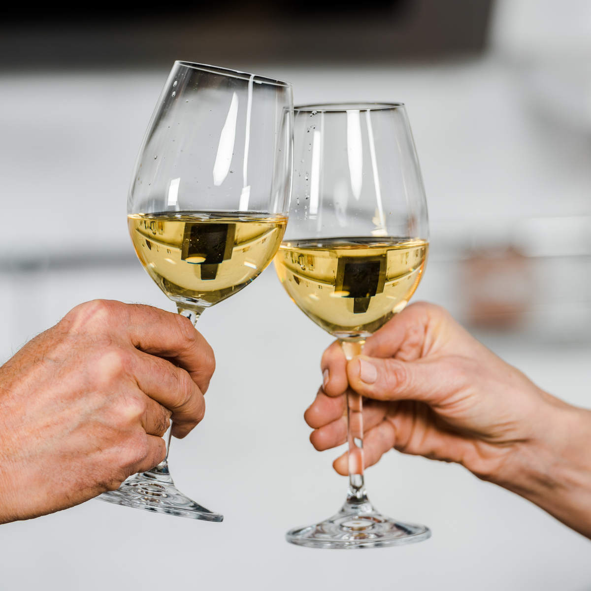 Two glasses of white wine being brought together.